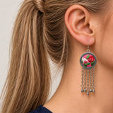 Close profile of a model wearing Petal Dialogue with red and white petals and green leaves on pink facing outward, above chains ending in three teardrops and two spheres.
