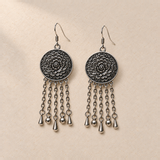 Petal Dialogue pair laid flat with floral metal reverses facing up; each has five oval-link chains ending in teardrop, sphere, teardrop, sphere and teardrop shapes.