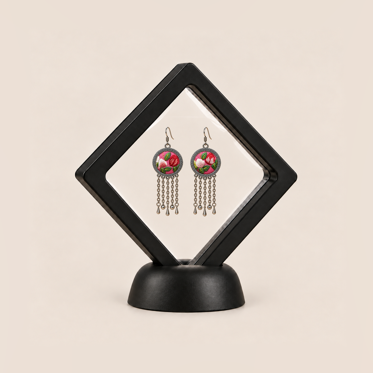 Petal Dialogue pair displayed in a black square clear-membrane frame on a black stand, with both pink floral embroidered fronts facing forward.