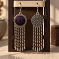 Crimson Confluence earrings hanging through holes in a pale textured strip on a rectangular wooden stand, showing the layered fabric front and floral reverse.