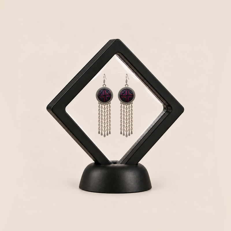 Crimson Confluence pair displayed in a black square clear-membrane frame on a black stand, with both dark layered fabric fronts facing forward.