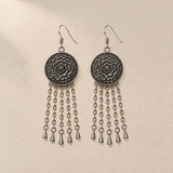 Golden Solace pair laid flat with round floral metal reverses facing up, each with five long oval-link chains ending in teardrop pendants.