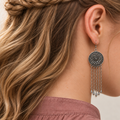 Close view of a model wearing the floral metal reverse of a Verdant Concord earring, with five long chains and teardrop pendants.