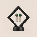 Verdant Concord earrings displayed in a tilted black square membrane frame on a round black base.