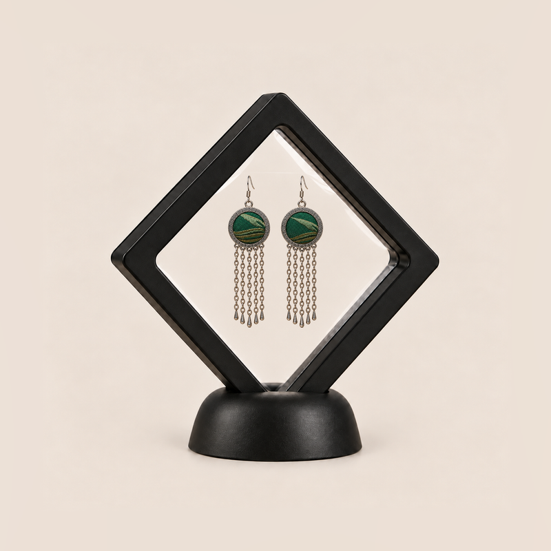Verdant Concord earrings displayed in a tilted black square membrane frame on a round black base.
