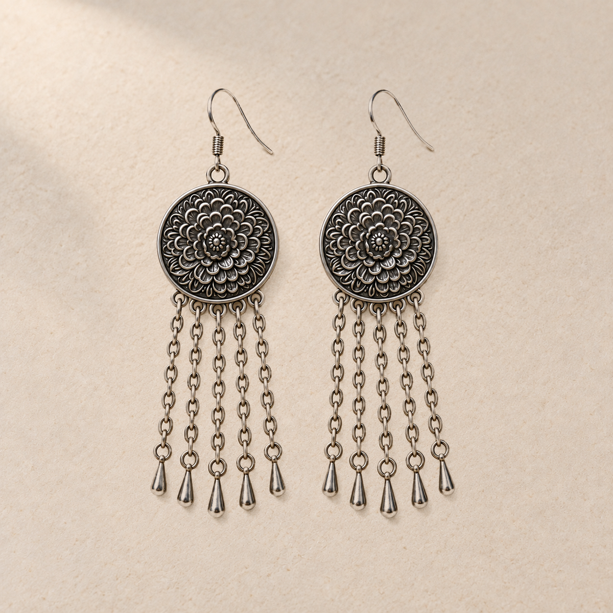 Pair of Scarlet Affinity floral metal reverses on cream cloth, with smooth outer rims and five long oval-link chains ending in teardrops.