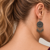 Model looking downward while wearing the floral metal reverse of a Garden Murmur earring with five flat leaf pendants on short chains.