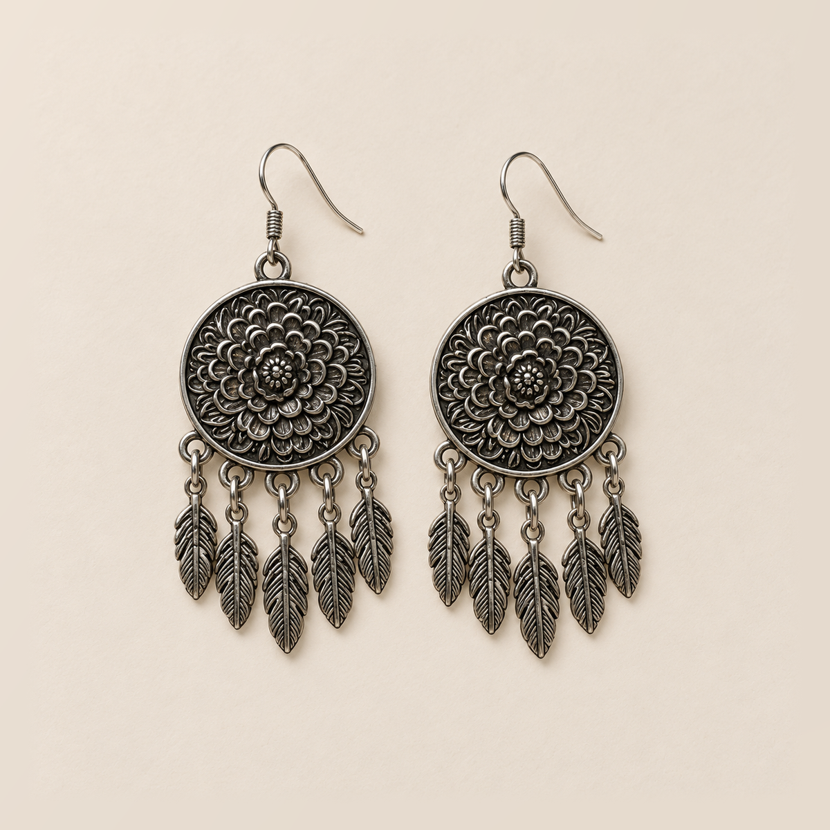Pair of Garden Murmur floral metal reverses on cream cloth, each with five short connecting chains and flat veined leaf pendants.