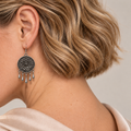 Model looking downward while wearing the floral metal reverse of an Azure Harmony earring with five short teardrop pendants.