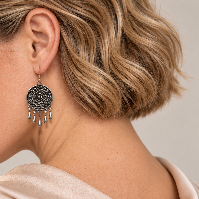 Model looking downward while wearing the floral metal reverse of an Azure Harmony earring with five short teardrop pendants.