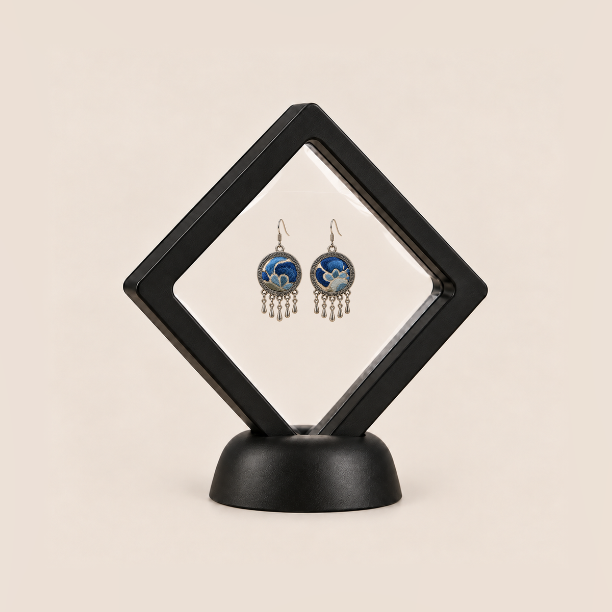 Azure Harmony drop earrings displayed in a tilted black square membrane frame on a round black base.