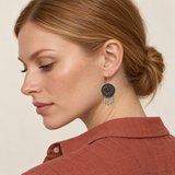 Model looking downward while wearing the floral metal reverse of a Teal Reverie earring with five short teardrop pendants.