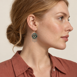 Teal Reverie earring worn at the ear, showing cream raised curves on teal and dark green embroidery with five short teardrop pendants.