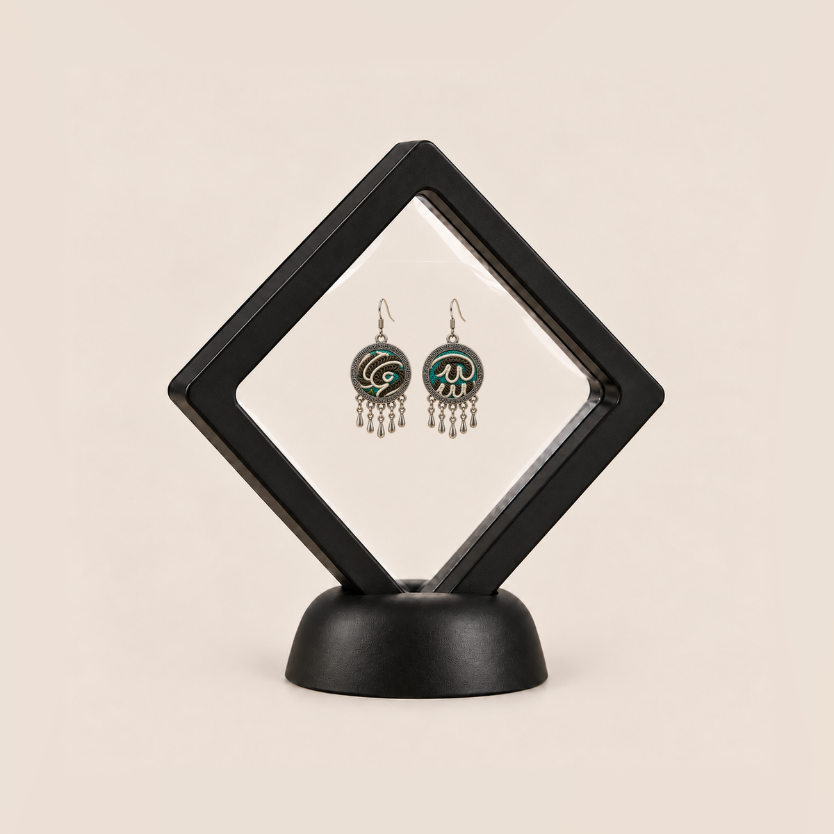 Teal Reverie drop earrings displayed in a tilted black square membrane frame on a round black base.