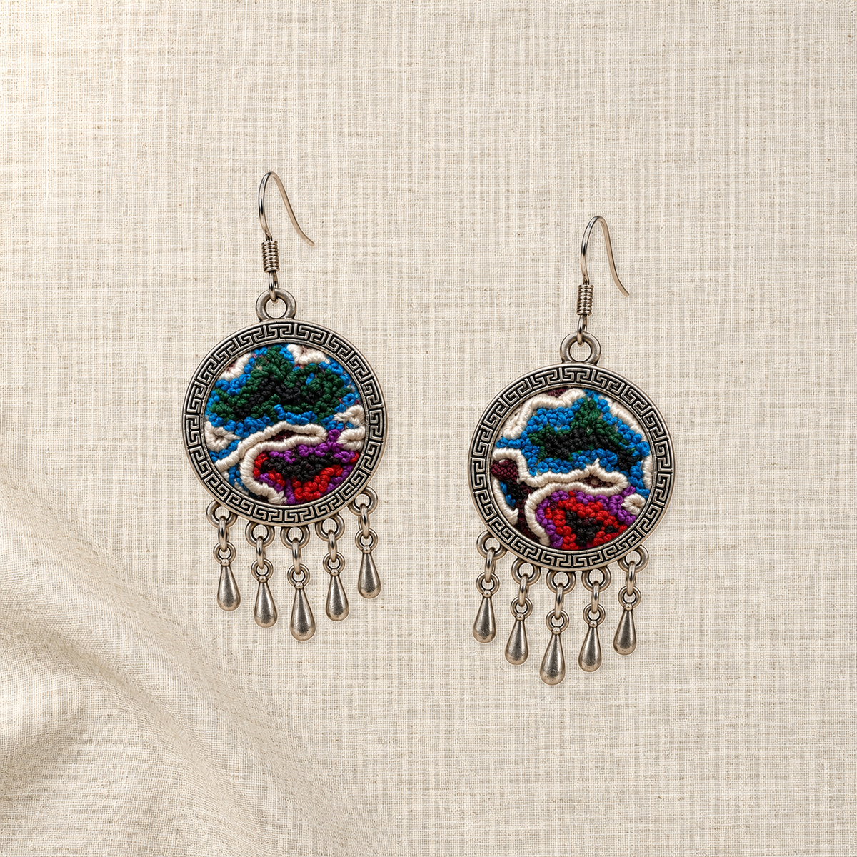 Both Chromatic Accord embroidered fronts face upward on plain cream woven cloth, with distinct colored knotted patterns and five short drops each.